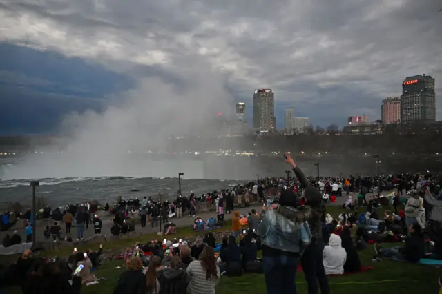 The sky darkens as people look up at the sun during the total solar eclipse across North America, at Niagara Falls State Park in Niagara Falls, New York, on April 8, 2024