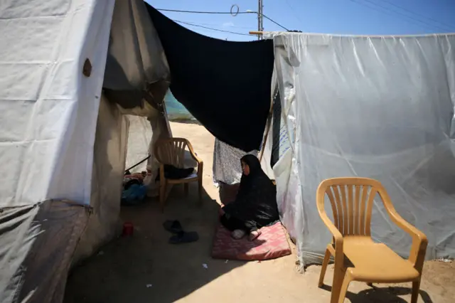 A Palestinian woman is seen in front of a makeshift tent in the city of Rafah