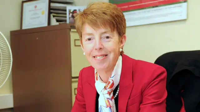 Ex-Post Office boss Paula Vennells pictured here smiling wearing a red blazer and decorative scarf