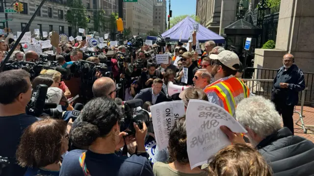 Members of the faculty and staff have gathered outside the entrance to Columbia University