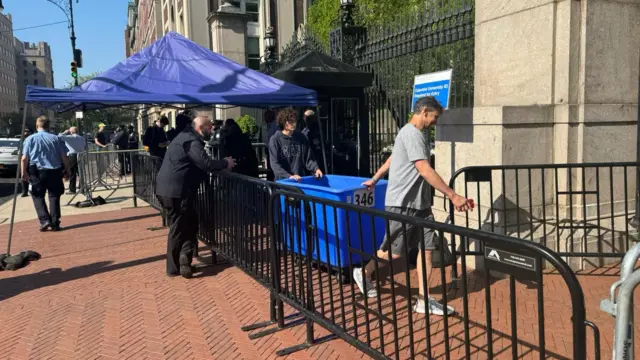 People stand by a temporary security cordon at the entrance to Columbia University