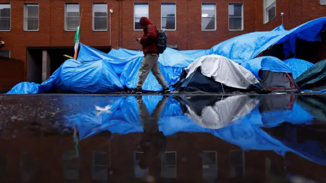 An asylum seeker walks by a temporary housing encampment for asylum seekers in Dublin