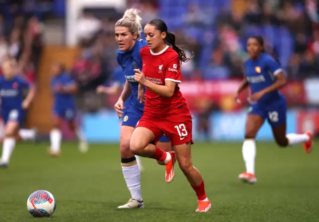 Mia Enderby of Liverpool runs with the ball whilst under pressure from Millie Bright of Chelsea