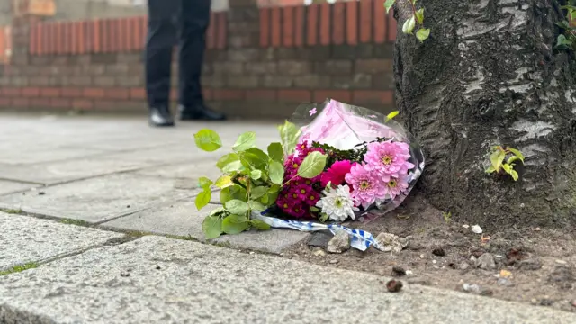 Picture of flowers by the floor on top of a police cordon tape