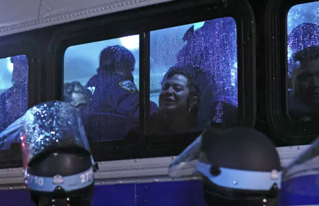 A student protester at the window of a police bus as she's taken away