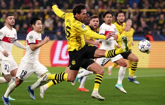 Mats Hummels (C) kicks the ball as PSG players look on