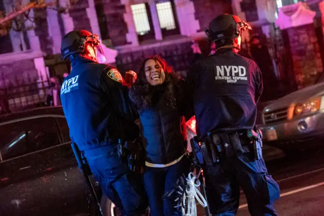 Two police drag away a female protester at City College of New York