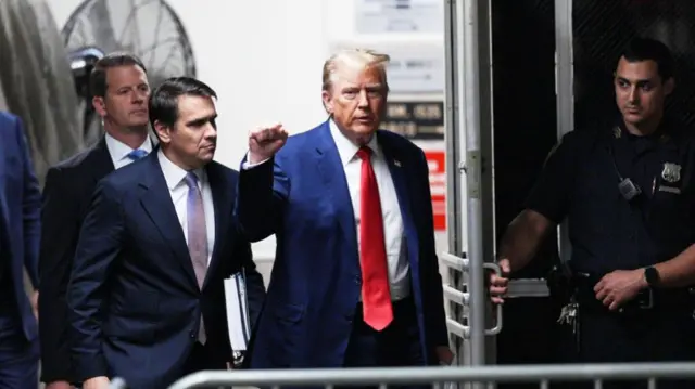 Donald Trump raises a fist outside court