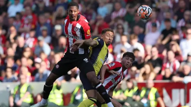 Ethan Pinnock (l) and Aaron Hickey of Brentford compete with Marcus Tavernier