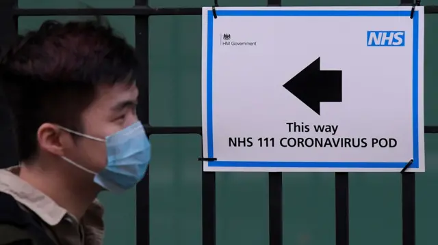 Man in mask walks past covid sign