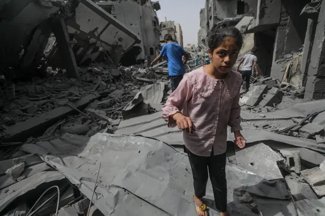 A Palestinian child walks on the rubble of her destroyed family house