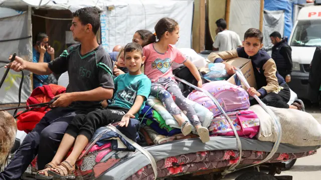 Children sit on top of belongings, as Palestinians prepare to evacuate Rafah