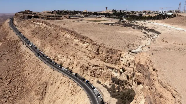 A drone view shows a trail of trucks lining up on a road near Mitzpe Ramon, southern Israel, on 9 May