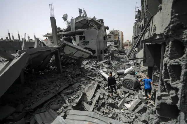 Palestinians look at the rubble of their destroyed houses after Israeli strikes