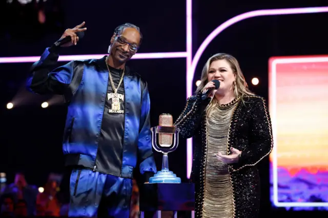 Snoop Dogg and Kelly Clarkson stand on stage at the American Song Contest in the US.