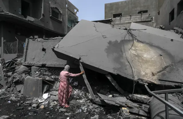 A Palestinian woman looks at what is left from her destroyed house aftermath of Israeli strikes overnight