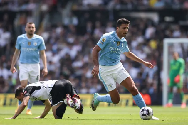 Manchester City's Spanish midfielder Rodri runs past Fulham's Portuguese midfielder Joao Palhinha