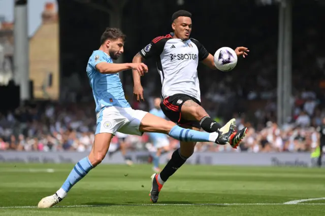 Manchester City's Ruben Dias battles for possession with Rodrigo Muniz of Fulham