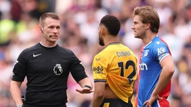 Referee Tom Bramall interacts with Matheus Cunha