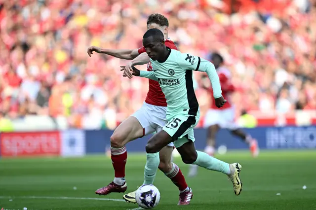 Nicolas Jackson of Chelsea runs with the ball under pressure from Ryan Yates of Nottingham Forest during the Premier League match between Nottingham Forest and Chelsea FC