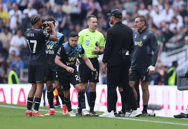 Referee Jarred Gillett speaks with Vincent Kompany the head coach