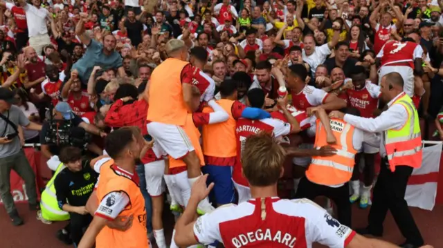 Arsenal players and fans celebrate their late win over Manchester United in September