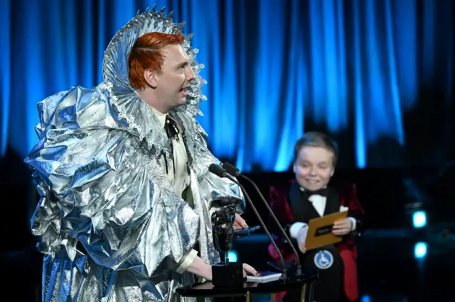 Dressed as Queen Elizabeth I, Joe Lycett accepts the award for entertainment performance