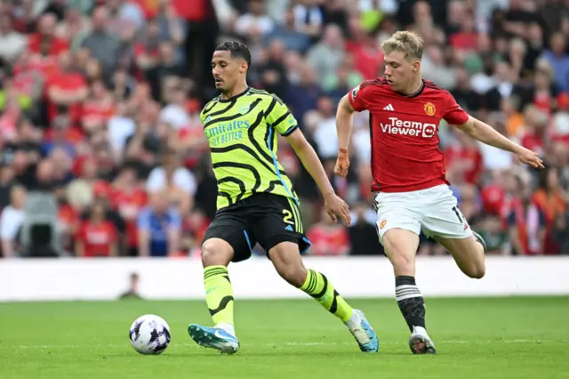 William Saliba of Arsenal runs with the ball whilst under pressure from Rasmus Hojlund of Manchester United during the Premier League match between Manchester United and Arsenal FC