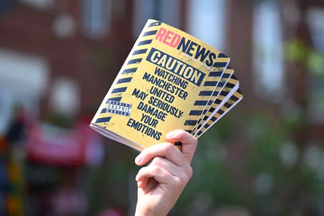 A detailed view of a copy of the RedNews magazine, which reads "Caution Watching Manchester United May Seriously Damage Your Emotions"