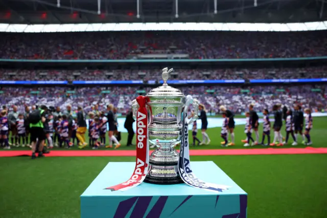 A detailed view of the Adobe Women's FA Cup trophy as players of Manchester United shakes hands with players of Tottenham Hotspur