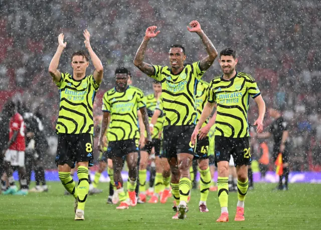 Martin Odegaard, Gabriel and Jorginho of Arsenal celebrate victory as they walk towards their fans after defeating Manchester United during the Premier League match between Manchester United and Arsenal FC