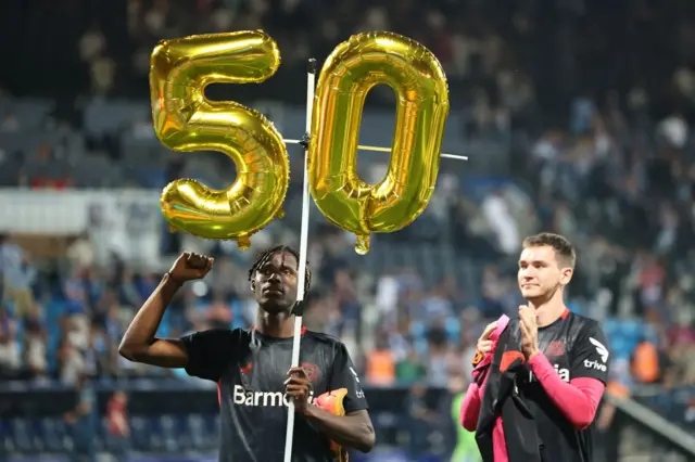 Odilon Kossounou holds up balloons after Bayer Leverkusen extended their unbeaten run to 50