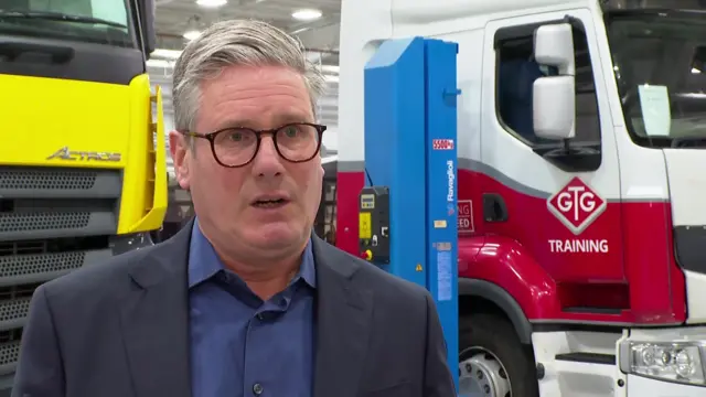 Keir Starmer speaks in front of two lorries