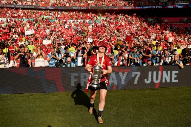 Aoife Mannion holds the FA Cup in front of Manchester United fans