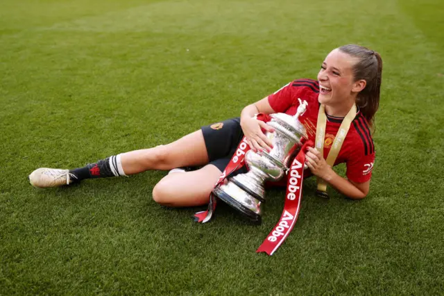 Ella Toone lies on the floor with the FA Cup trophy