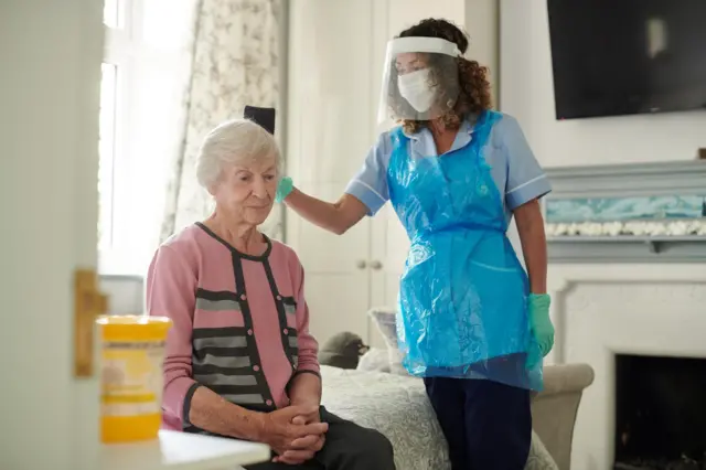 Nurse caring for elderly woman in care home