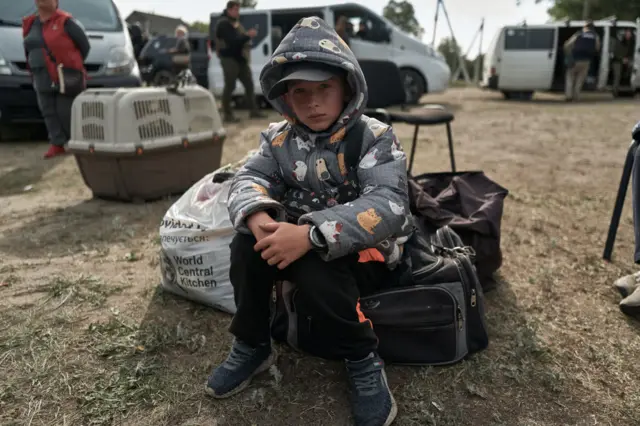 A young child sits on his bag as the Kharkiv coordination volunteer center, together with the national police and emergency services conducts an evacuation from the pro-front city on the border with Russia on May 13, 2024 in Vovchansk Kharkiv Region, Ukraine