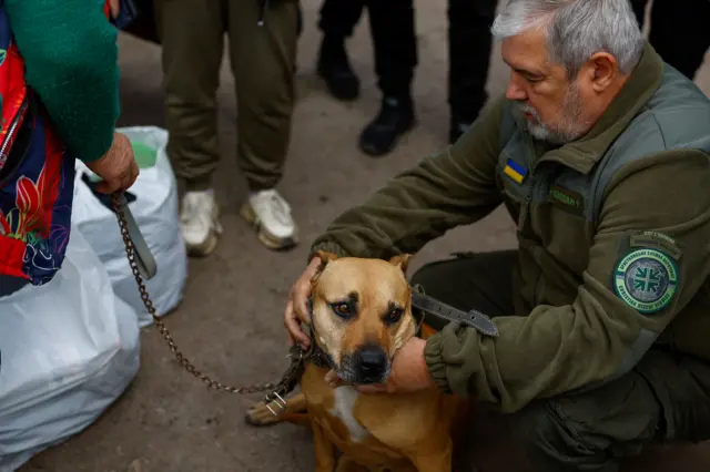 A military chaplain kneels with a nervous dog