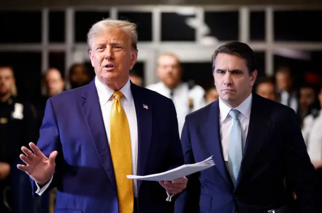 Donald Trump outside court holding papers