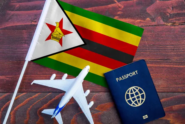 Flag of Zimbabwe with passport and toy airplane on wooden background. - stock photo