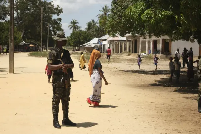 A mozambican soldier looks on as civilians are seen in Quionga, Mozambique, on September 30, 2022. - In March 2021, fighters affiliated to the Islamic State group attacked the port city of Palma -- the jewel in the crown of a gas project that would supposedly shower Cabo Delgado province with good jobs and desperately-needed infrastructure. (Photo by Camille LAFFONT / AFP) (Photo by CAMILLE LAFFONT/AFP via Getty Images)