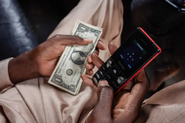 A street currency dealer uses a smartphone calculator app to calculate the rate for exchanging US dollar banknotes at a market in Lagos, Nigeria, on Monday, Sept. 25, 2023