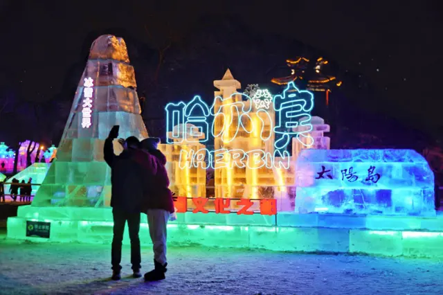 Tourists look at illuminated ice sculptures in Harbin