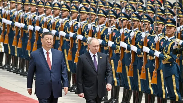 Chinese President Xi Jinping (left) walks beside Russian President Vladimir Putin with rows of soldiers in the background.