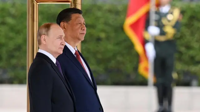 Russian President Vladimir Putin and Chinese President Xi Jinping stand next to one another in close up while staring into the distance.