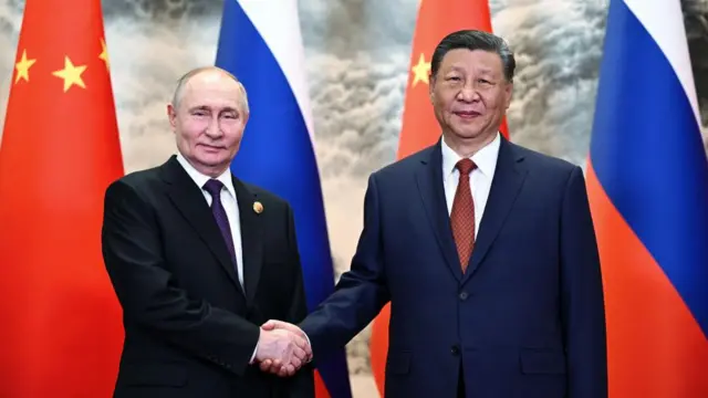 Russian President Vladimir Putin (L) and Chinese President Xi Jinping shake hands as they pose for photos before a meeting in narrow format at the Great Hall of the People in Beijing, China