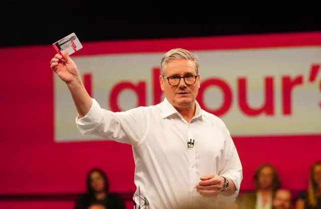 Starmer shows the "my first steps" pledge card to the audience in Essex