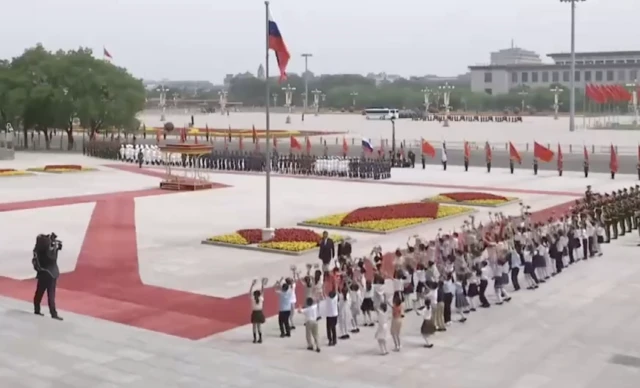 Children cheer and wave pompoms as the two leaders pass by