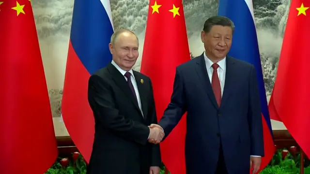 Putin and Xi shaking hands at their first meeting of the day