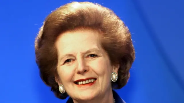 Margaret Thatcher smiling in front of a blue background